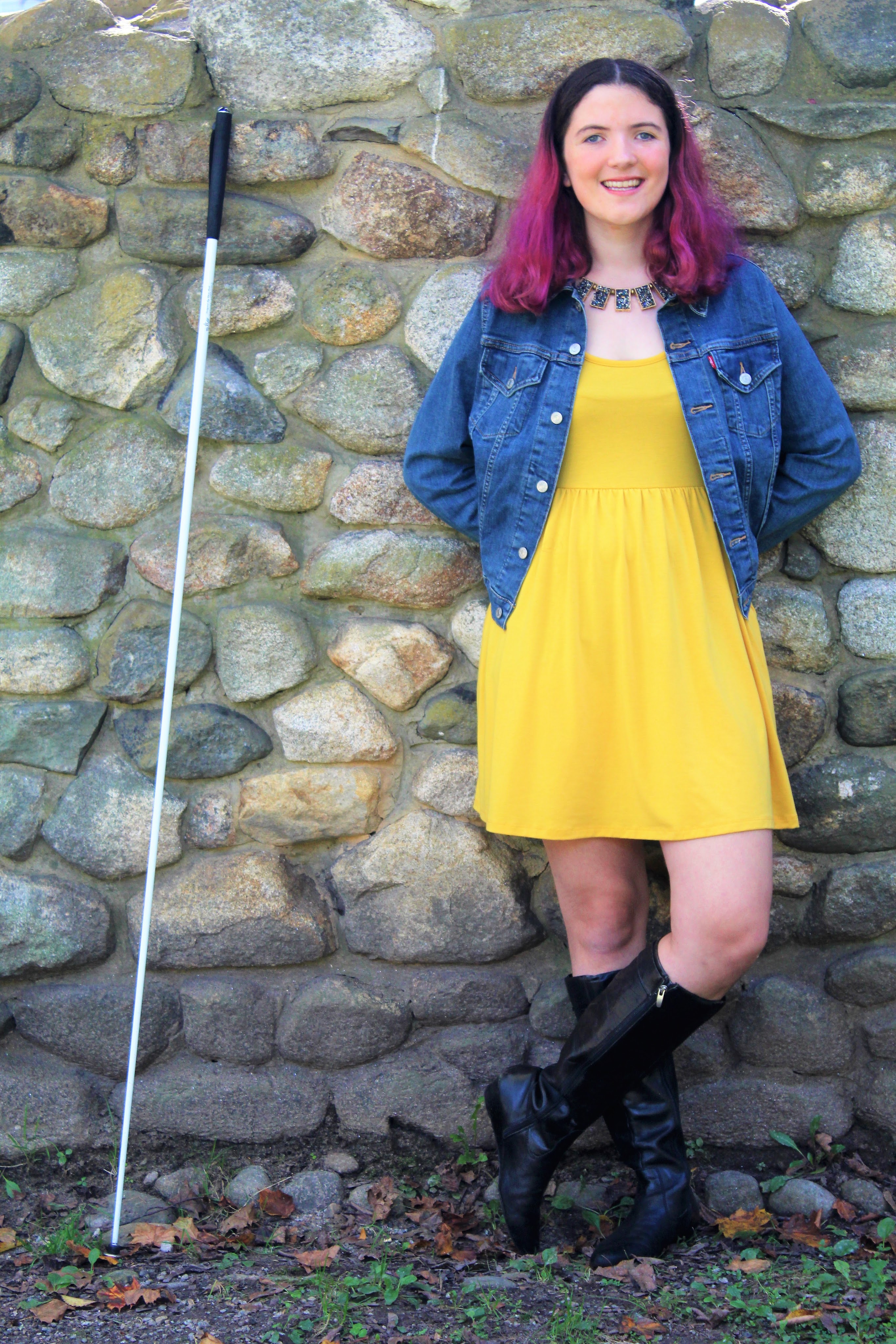 Abby smiling against a stone wall with her white can next to her. 