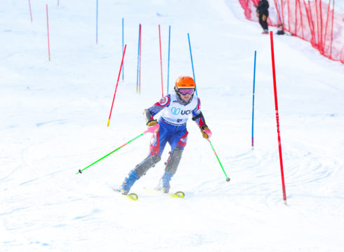 Abby skiing a slalom course between red and blue gates.